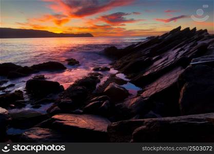 Sunset on ocean beach with rocks