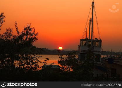 Sunset on the beach with a ship in the foreground