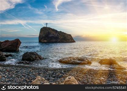 Sunset on the beach with sea, rocks and dramatic sky