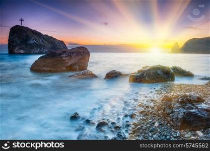 Sunset on the beach with sea, rocks and dramatic sky. Seaside landscape
