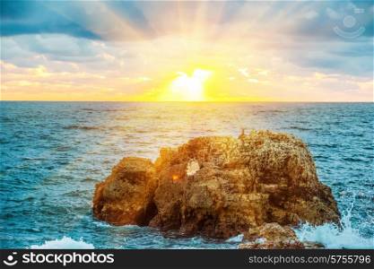 Sunset on the beach with waves, sea, rocks and dramatic sky