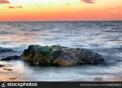 Sunset on the sea. Landscape with big rock and beautiful orange sky.