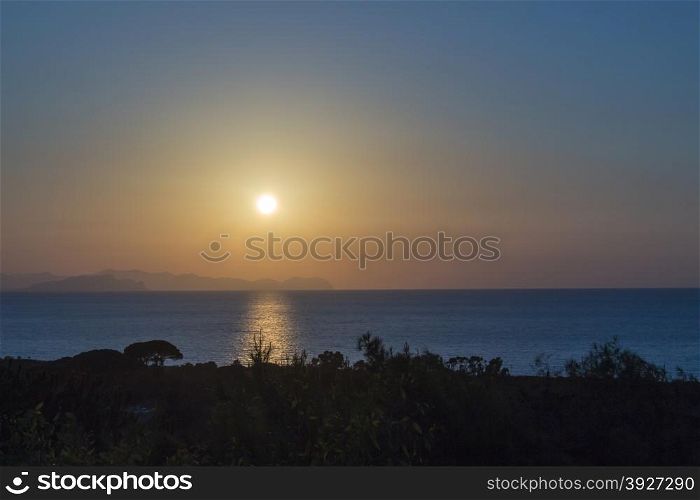 Sunset on the sea of sicily with trees.