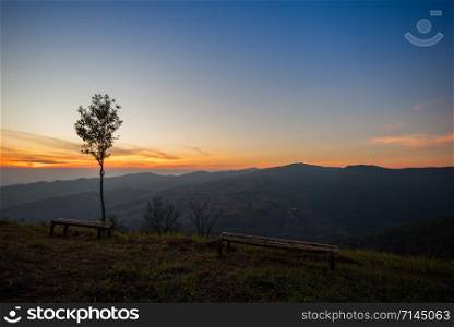 Sunset or sunrise on viewpoint hill mountain yellow and blue sky with tree and bamboo bench