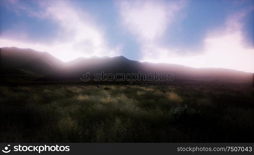 Sunset over a green grassy rocky hills