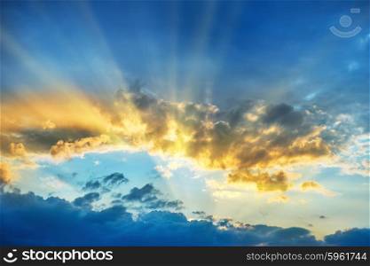 Sunset over beautiful blue sky with sun shining through clouds