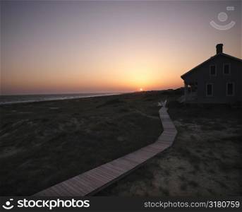 Sunset over coastal beach house with wooden boardwalk at Bald Head Island, North Carolina.