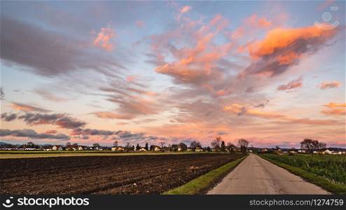 Sunset over fields and Austrian village with dramatic sky and colorful clouds. Sunset over village with dramatic sky