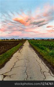 Sunset over fields and Austrian village with dramatic sky and colorful clouds. Country road in Austria. Sunset over village with dramatic sky