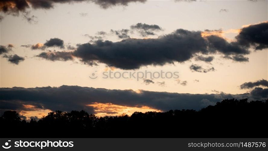 Sunset over forest with dramatic sky and colorful dark clouds. sky background. Sunset over forest with dramatic sky and colorful dark clouds