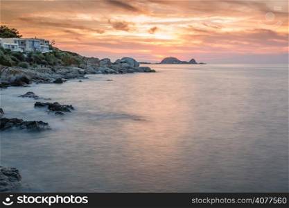 Sunset over Ile Rousse in the Balagne region of Corsica with rocks in foreground