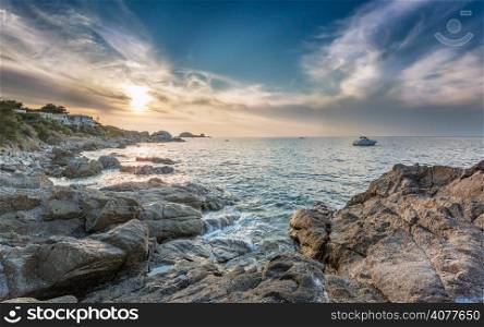Sunset over Ile Rousse in the Balagne region of Corsica with rocks in foreground