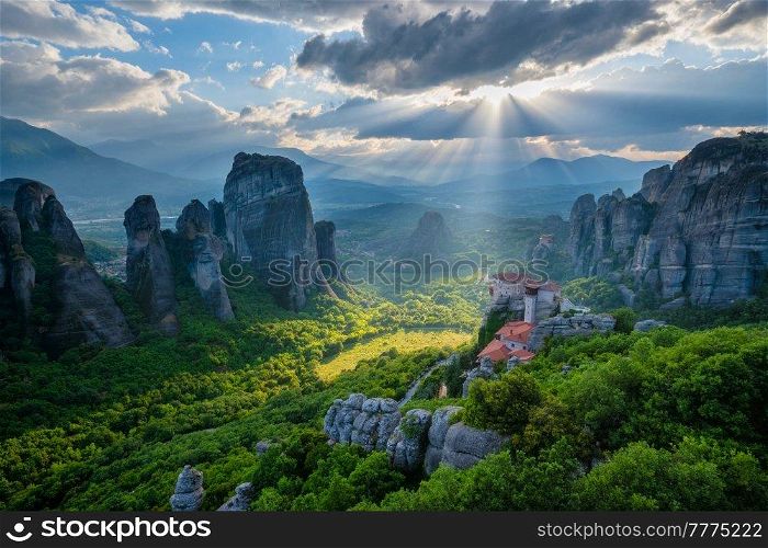 Sunset over monastery of Rousanou and Monastery of St. Nicholas Anapavsa in famous greek tourist destination Meteora in Greece on sunset with sun rays and lens flare and dramatic sky. Sunset over monasteries of Meteora