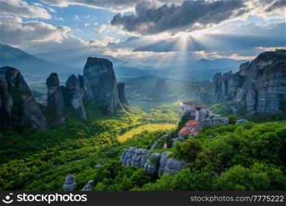 Sunset over monastery of Rousanou and Monastery of St. Nicholas Anapavsa in famous greek tourist destination Meteora in Greece on sunset with sun rays and lens flare and dramatic sky. Sunset over monasteries of Meteora