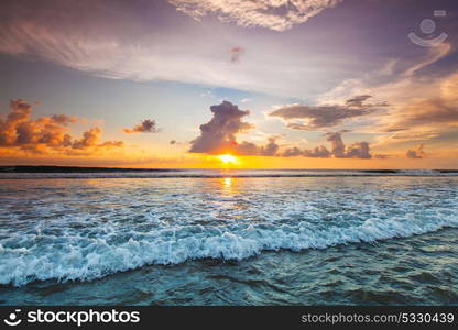 Sunset over ocean. Splashing ocean wave in front of beautiful sunset sky background