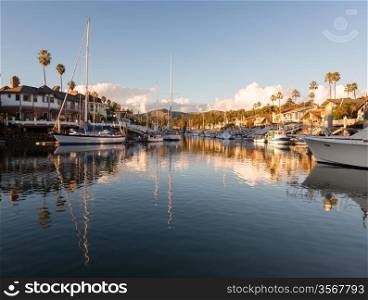 Sunset over residential development by water in Ventura California with modern homes and yachts boats
