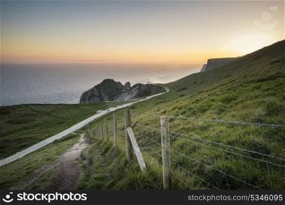 Sunset over sea stack on English coast during Spring with tourists on footpath