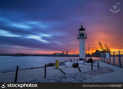 Sunset over the lighthouse at the port