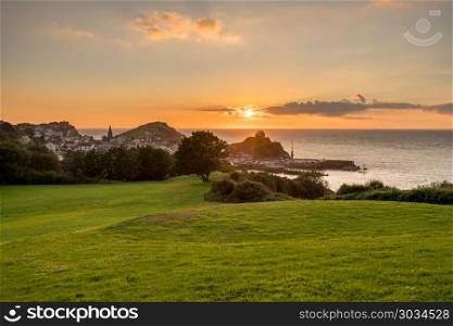 Sunset over the tourist town of Ilfracombe in Devon. Panorama of the seaside town of Ilfracombe in Devon at sunset with view over harbor and houses. Sunset over the tourist town of Ilfracombe in Devon