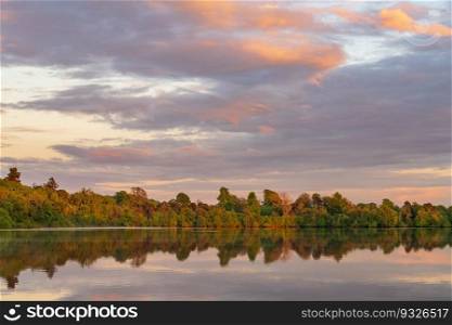 Sunset panorama of the lake shore of the Mere with a perfect lake reflection in Ellesmere in Shropshire. View across the Ellesmere Mere to a clear reflection of distant trees