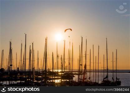 Sunset paragliding over yachts silhouette and sun sea