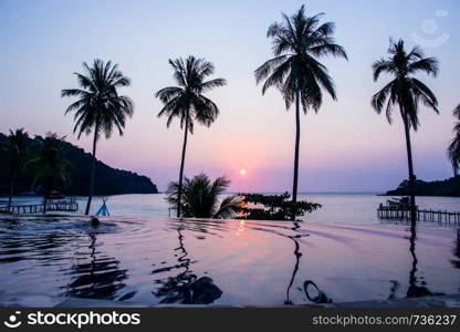 Sunset reflecting on the water surface foreground with coconut trees area ao bang bao at Koh kood island is a district of Trat Province. Thailand.