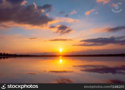 Sunset reflection lagoon. beautiful sunset behind the clouds and blue sky above the over lagoon landscape background. dramatic sky with cloud at sunset