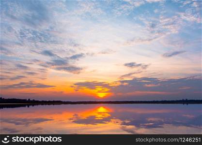 Sunset reflection lagoon. beautiful sunset behind the clouds and blue sky above the over lagoon landscape background. dramatic sky with cloud at sunset