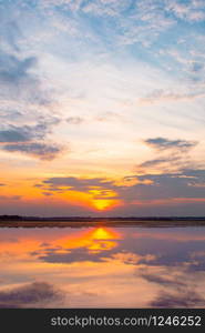 Sunset reflection lagoon. beautiful sunset behind the clouds and blue sky above the over lagoon landscape background. dramatic sky with cloud at sunset