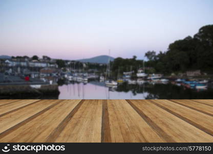 Sunset reflections of boats in harbour in Summer with wooden planks floor