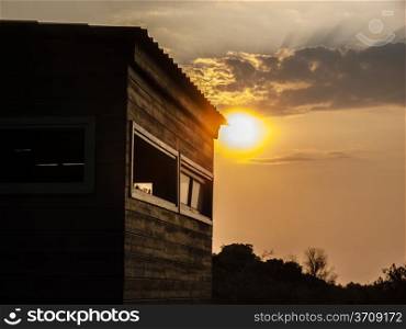Sunset scene in the forest with a wooden house