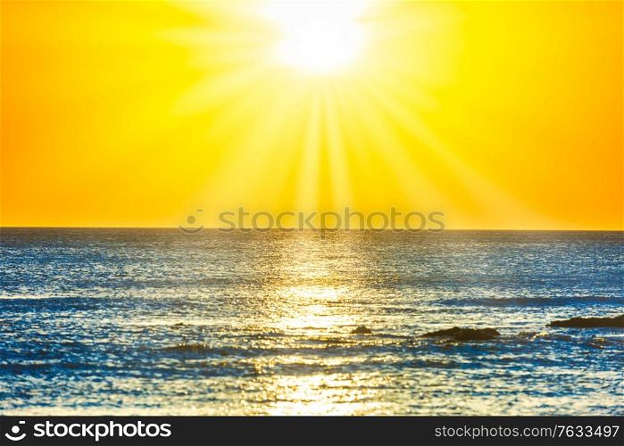 Sunset sea and beach with rocks and sunset sun on dramatic sky