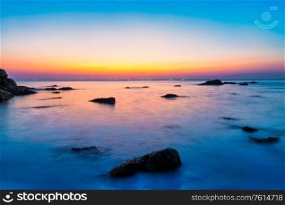 Sunset sea with rocks and evening sunset sun on dramatic sky