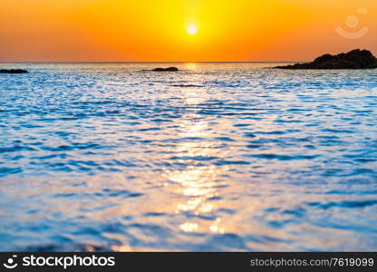 Sunset sea with rocks and evening sunset sun on dramatic sky