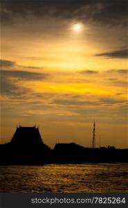 Sunset silhouette of the temple and communications station. Adjacent river. During the evening.