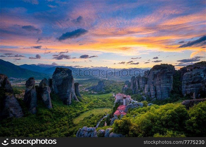 Sunset sky and monastery of Rousanou and Monastery of St. Nicholas Anapavsa in famous greek tourist destination Meteora in Greece with sun rays and lens flare. Sunset sky and monasteries of Meteora