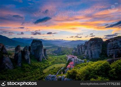 Sunset sky and monastery of Rousanou and Monastery of St. Nicholas Anapavsa in famous greek tourist destination Meteora in Greece with sun rays and lens flare. Sunset sky and monasteries of Meteora