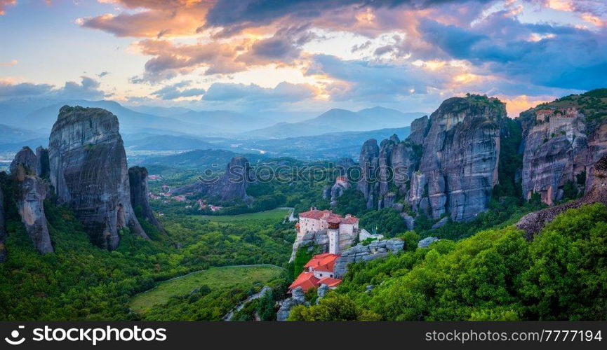 Sunset sky and monastery of Rousanou and Monastery of St. Nicholas Anapavsa in famous greek tourist destination Meteora in Greece with sun rays and lens flare. Sunset sky and monasteries of Meteora