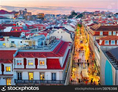 Sunset sky over evening Lisbon skyline with rooftops of historical old town, illuminated shopping street, Portugal