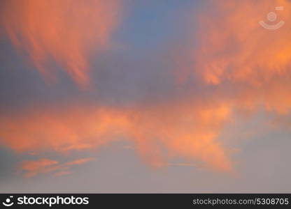 Sunset sky with orange golden clouds on blue background