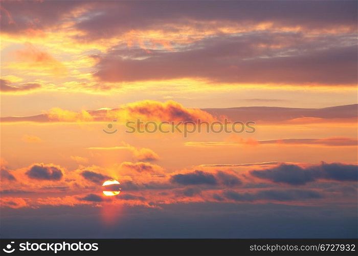 sunset sky with sun under clouds