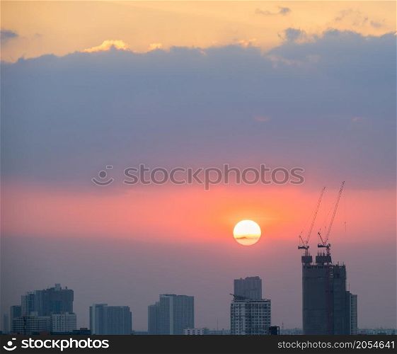 Sunset skyline over high rise buildings and construction site with cranes