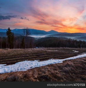 Sunset spring Carpathian mountains plateau landscape with snow-covered ridge tops in far, Ukraine.