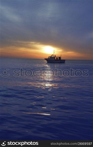 sunset sunrise with fishing boat in horizon blue mediterranean sea