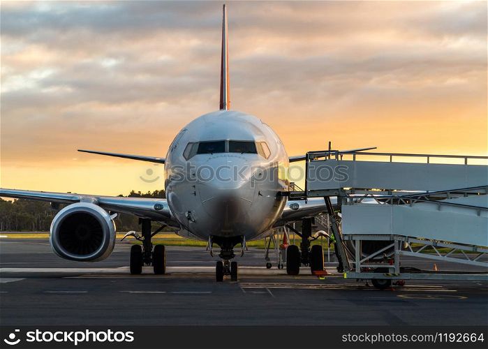 Sunset view of airplane on airport runway under dramatic sky in Hobart,Tasmania, Australia. Aviation technology and world travel concept.