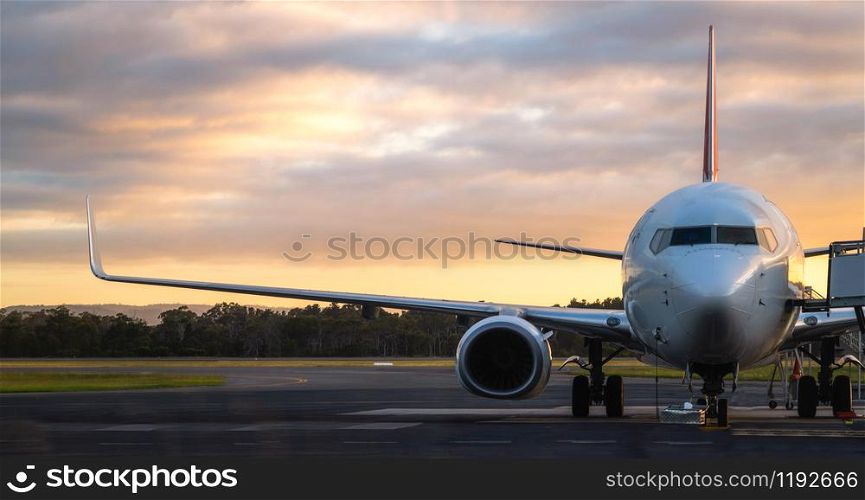 Sunset view of airplane on airport runway under dramatic sky in Hobart,Tasmania, Australia. Aviation technology and world travel concept.