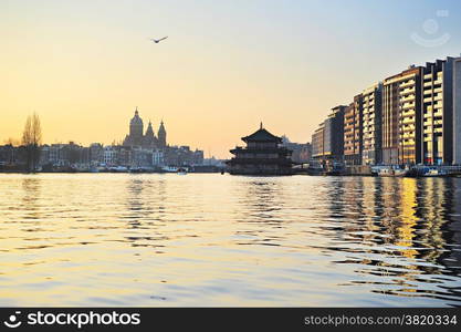 Sunset view of Amsterdam with reflection in the river. Holland