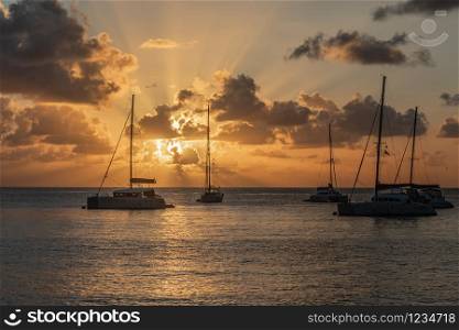 Sunset view of yachts and catamarans anchored in the lagoon, Britannia bay, Mustique island, Saint Vincent and the Grenadines, Caribbean sea