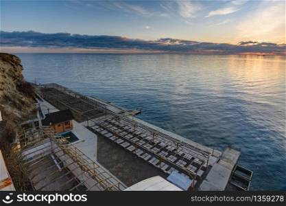 Sunset view on an empty sunlounge beach on a rocky sea shore