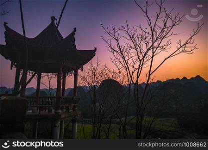 Sunset with pavilion and Rapeseed flower field at Wanfenglin National Geological Park (Forest of Ten Thousands Peaks), China